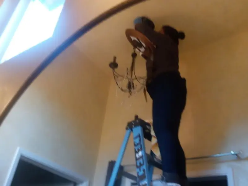 Electrician installing a chandelier in a Blackfoot residence
